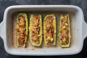 Baked stuffed zucchini boats with minced chicken mushrooms and vegetables with cheese on a baking sheet. Top view Copy space