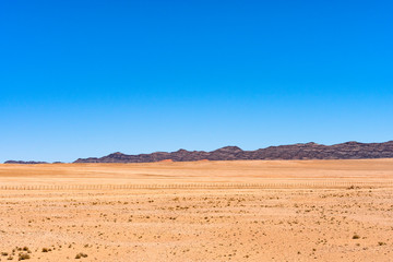Fototapeta na wymiar Beautiful view of desert with clear blue sky from road trip in NAMIBIA