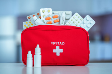 Medical first aid kit with medicine and pills on table at home