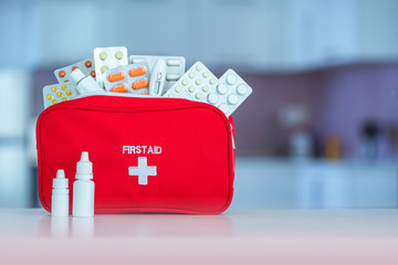 Medical first aid kit with medicine and pills on table at home