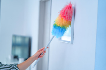 Housewife wipes dust with a dust brush at home. Household chores and housekeeping
