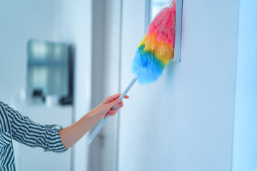 Housewife wipes dust with a dust brush during spring cleaning at home. Household chores and housekeeping