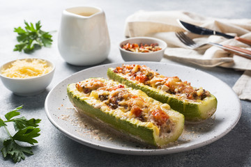 Baked stuffed zucchini boats with minced chicken mushrooms and vegetables with cheese on a plate. - Powered by Adobe
