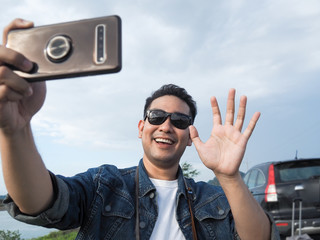 Asian tourist taking photo by his smart phone while on road trip, lifestyle concept.