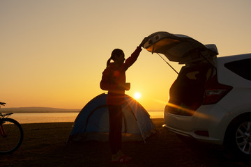 Woman camping activity with a car on the location during sunrise