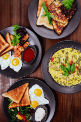Traditional breakfast with fried eggs, sausages, beans, mushrooms, grilled tomatoes and bacon on wooden background. Top view