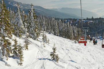 Cable cars and chair lifts in ski resort . Mountains with white snow, blue sky. Downhill fun at...