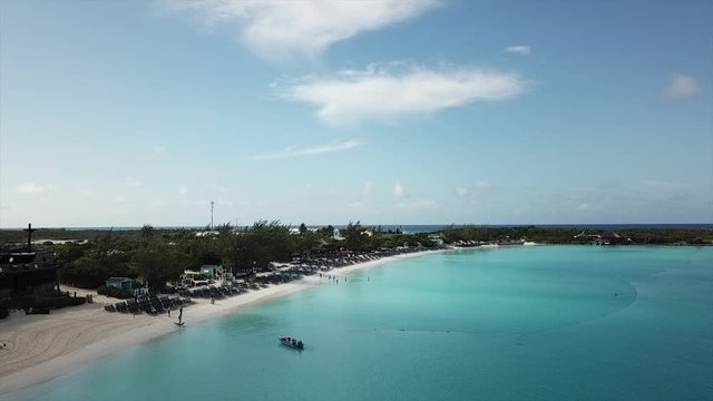 Slow drone footage flying over beautiful sandy beach and turquoise water in Bahamas Island of Half moon cay
