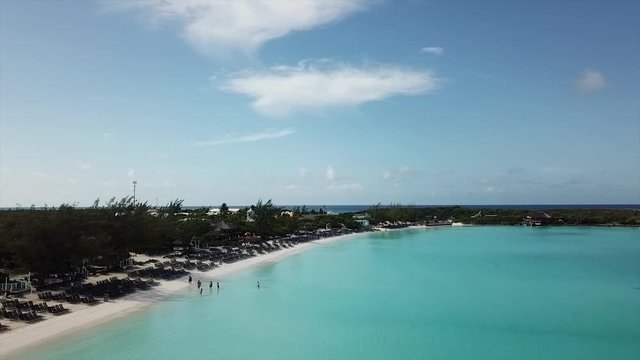Drone footage flying over beach with  crystal clear water slow  rotation to open sea Bahamas island Half Moon Cay