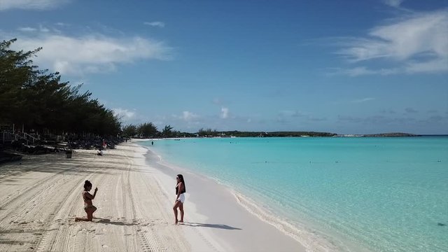 Slow low flight footage over sunny sandy beach and turquoise water of Bahamas island Half Moon Cay