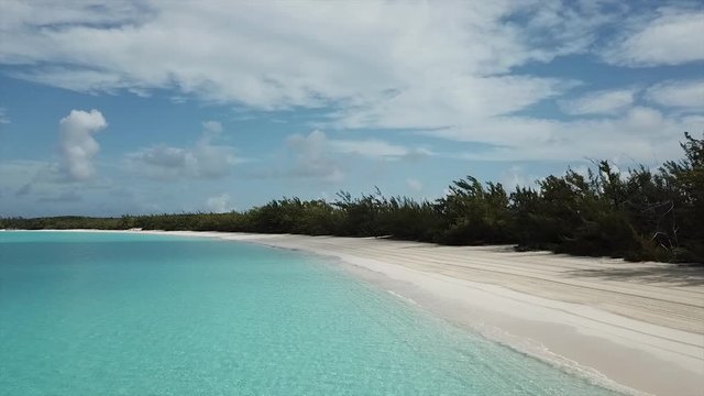 Slow drone  footage flying low over crystal clear waters on sandy beach Bahamas Island Half Moon Cay in the morning with no humans