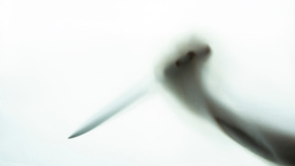 Blurred shadow of hand holding big sharp knife on white background.Robber,murderer or killer with...