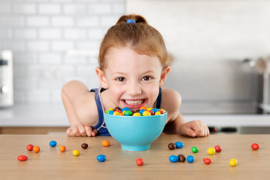 Cute little girl smiling next to candy bowl