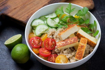 Bowl with quinoa, fried cheese, cherry tomatoes, cucumber and parsley, studio shot, selective focus