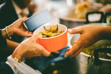 Giving food to the poor, the hands of beggars receive charity food from service providers: concept of poverty and food shortage
