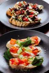 Italian Appetizer Bruschetta with roasted tomatoes, mozzarella cheese, garlic and herbs on wooden table