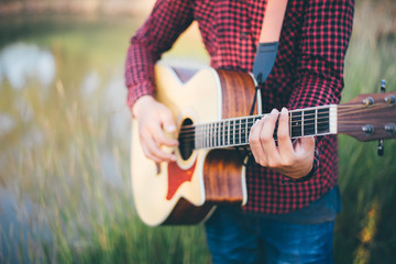 Music in nature, Man playing an acoustic guitar in meadow, Close-up, Copy-space