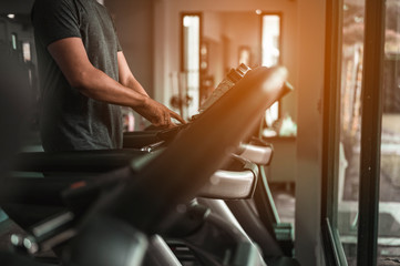 Close-up a young gymer is jogging on a treadmill in a modern fitness center for good health and strength.