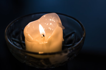 Candle light warming blue hour, melting wax in glass dish.