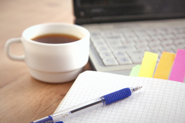 Office table with blank notepad and laptop