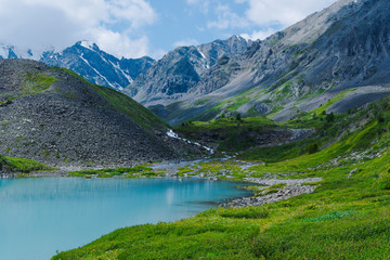 Fototapeta na wymiar Turquoise lake among mountain peaks. High mountain river on summer day, hiking on rocks and stones