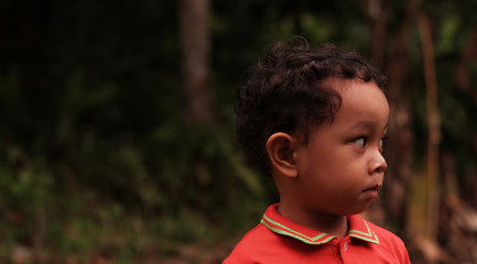 Portrait of a little Asian boy in red with a funny expression. Indonesian cute kid.