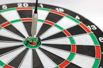Miniature people digging the arrow in the middle of the target to the dart board. Concept of doing for goals.