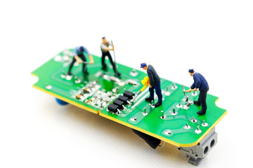 Miniature people: Engineers fixing error on chip of circuit board. Computer repair concept.