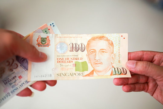 Hand hold a 100 singapore dollar banknote ready for shopping, Singapore currency many value in shopping.