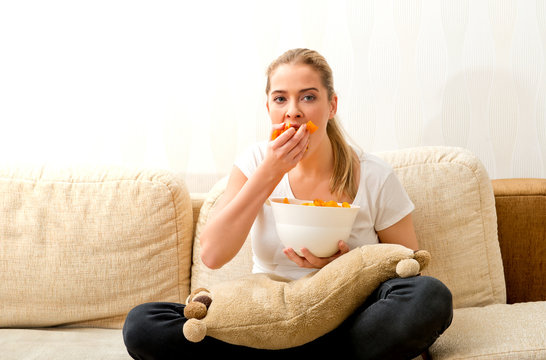 Woman Eating Chips And Watching Tv. She Is Stressed And She Eating Junk Food.