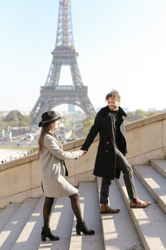 Afro american man and girl holding hands and walking on stairs, Eiffel Tower in background, Paris.