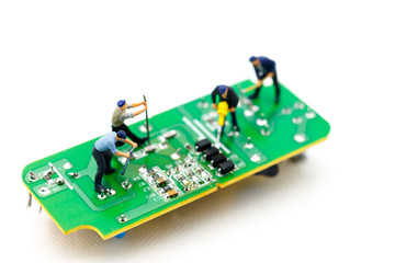 Miniature people: Engineers fixing error on chip of circuit board. Computer repair concept.