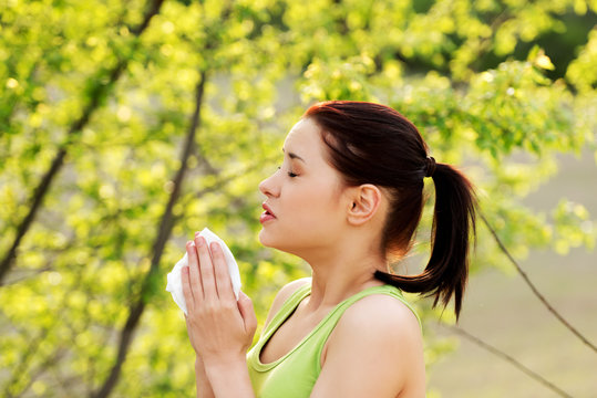 Side View Of Woman Sneezing In Tissue Because Of Allergy On Pollen, Outdoor.