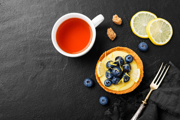 Obraz na płótnie Canvas Blueberry tartlet, pie, tart with lemon custard. Black stone background.