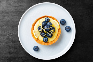 Blueberry tartlet, pie, tart with lemon custard. Black  background.