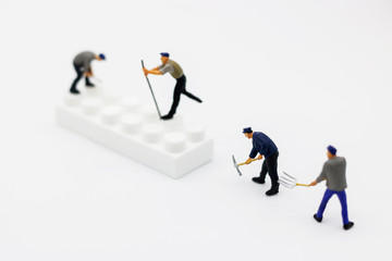 Fototapeta premium Miniature people: Worker digging white box. Service, repair and maintenance concept.