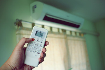 Air conditioner inside the room with man open or close remote controller.  Air conditioner with...