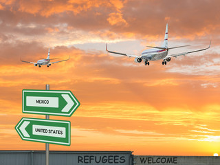 Digital composite and 3D illustration of two passenger jet airliners flying into a red sunset sky with arrow signs of the United States and Mexico and refugees welcomed on a wall in the foreground    - Powered by Adobe