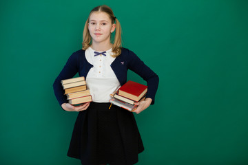 schoolgirl girl stands with books in the classroom
