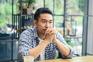 Fototapeta na wymiar Depressed Asian man using smartphone in cafe, lifetyle concept.