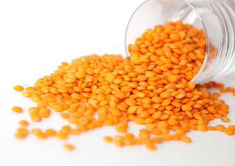 Red lentils on white background. Different forms of dry lentils. Lentils red in a transparent glass jar. Handful of legumes.
