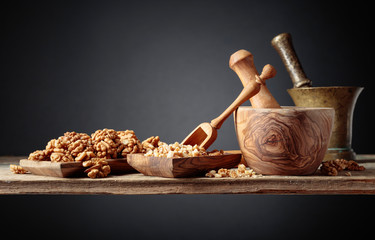 Crushed and whole walnuts in a wooden dish on an old wooden table.