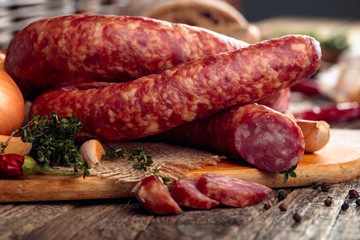 Dry-cured sausage with bread and spices on a old wooden table.