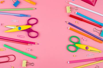 Colorful school supplies over a paper on pink background with place for your text