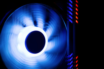 Fragment of the computer case.  Powerful computer cooler in motion with blue backlight.  CPU Cooler. RAM is highlighted in red ans blue