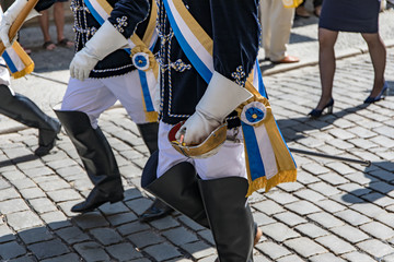 Close-up of uniform of members of student fraternity walking on cobbled street - obrazy, fototapety, plakaty