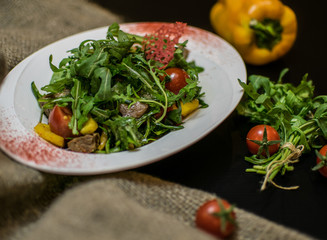 salad with arugula and cherry tomatoes on a black background