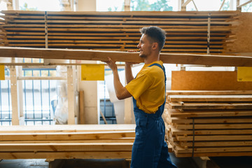 Male builder holds wooden boards in hardware store