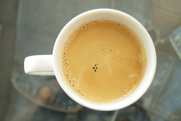 Espresso coffee in a white mug on a denim shirt