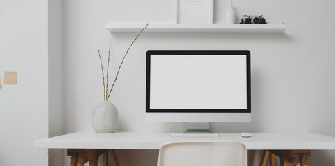 Modern workspace with blank screen desktop computer and decorations on white table and white wall